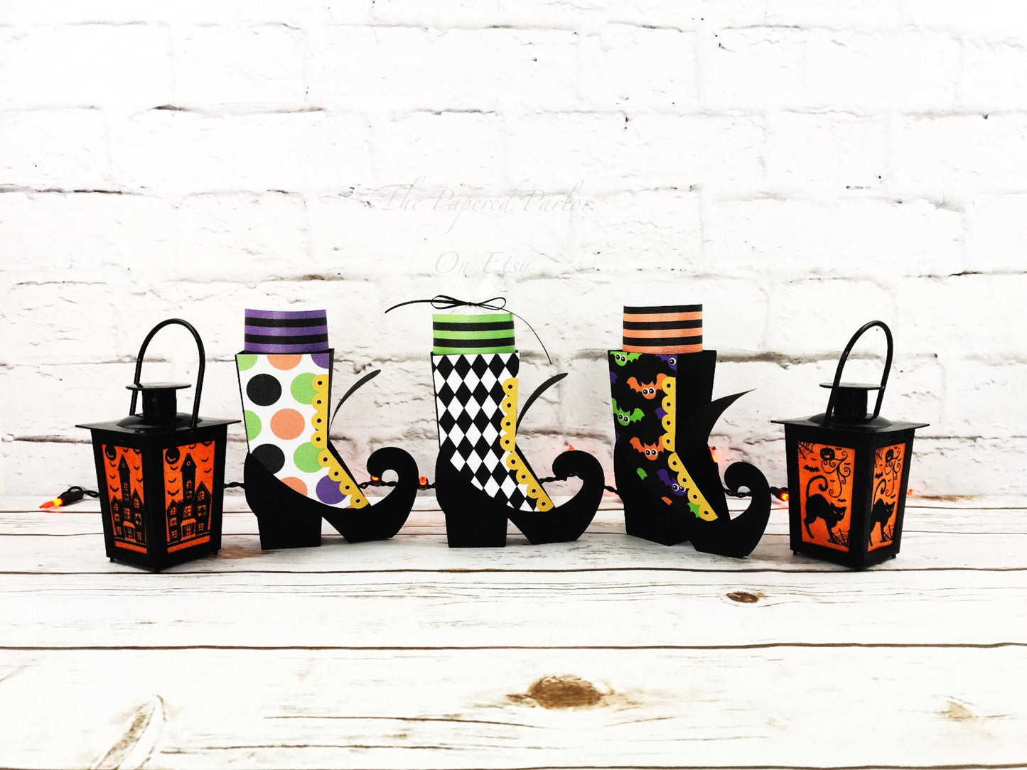 witch boot party box. the witch boots are black but designed with different outer design. the outer designs are circles, a black and white argyle design and a bat design. the witch party boxes have striped socks that adorn the top of the boot.