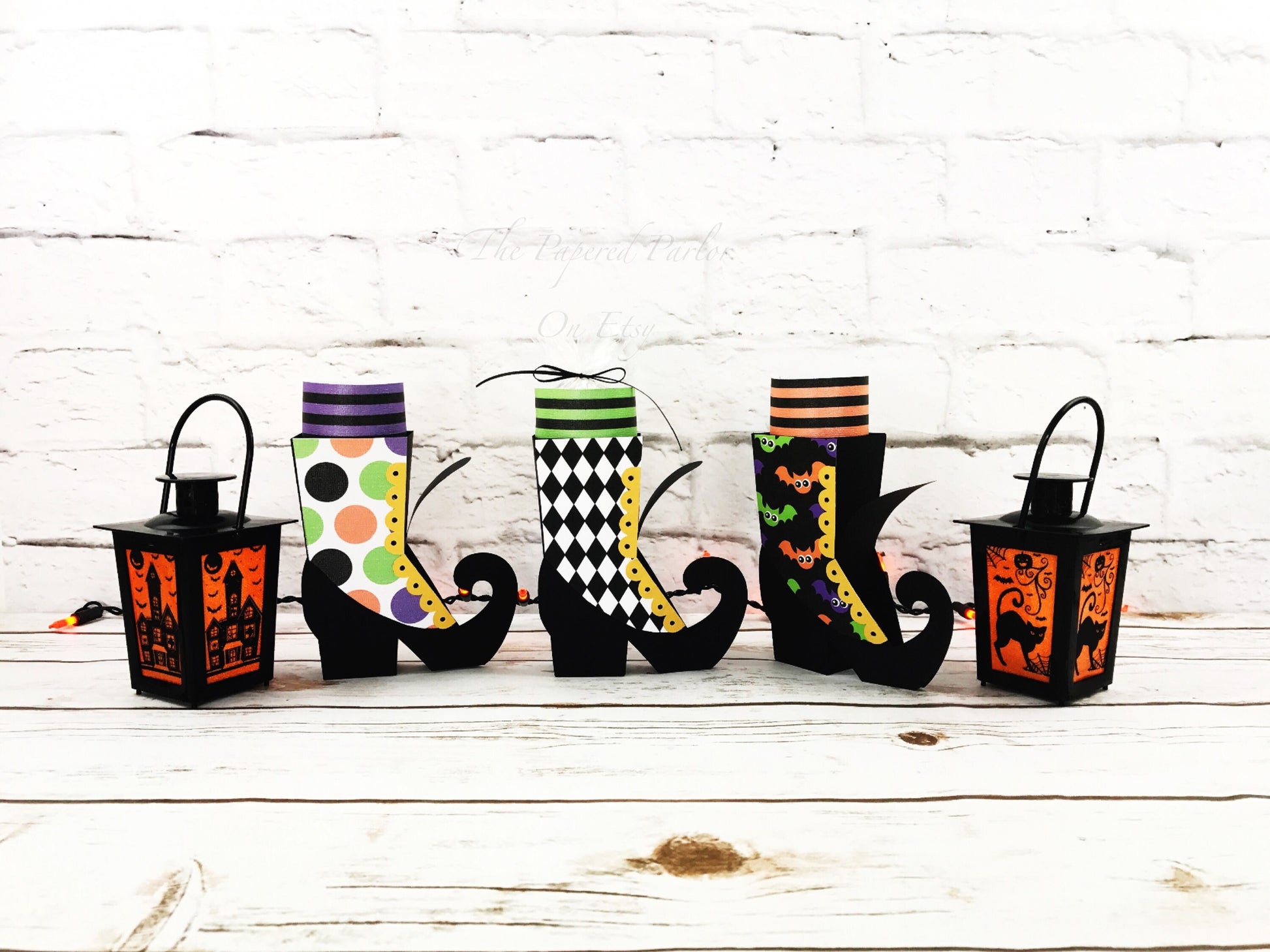 Witch boot party box. The witch boots are black but designed with different outer design. The outer designs are circles, a black and white argyle design and a bat design. The witch party boxes have striped socks that adorn the top of the boot.