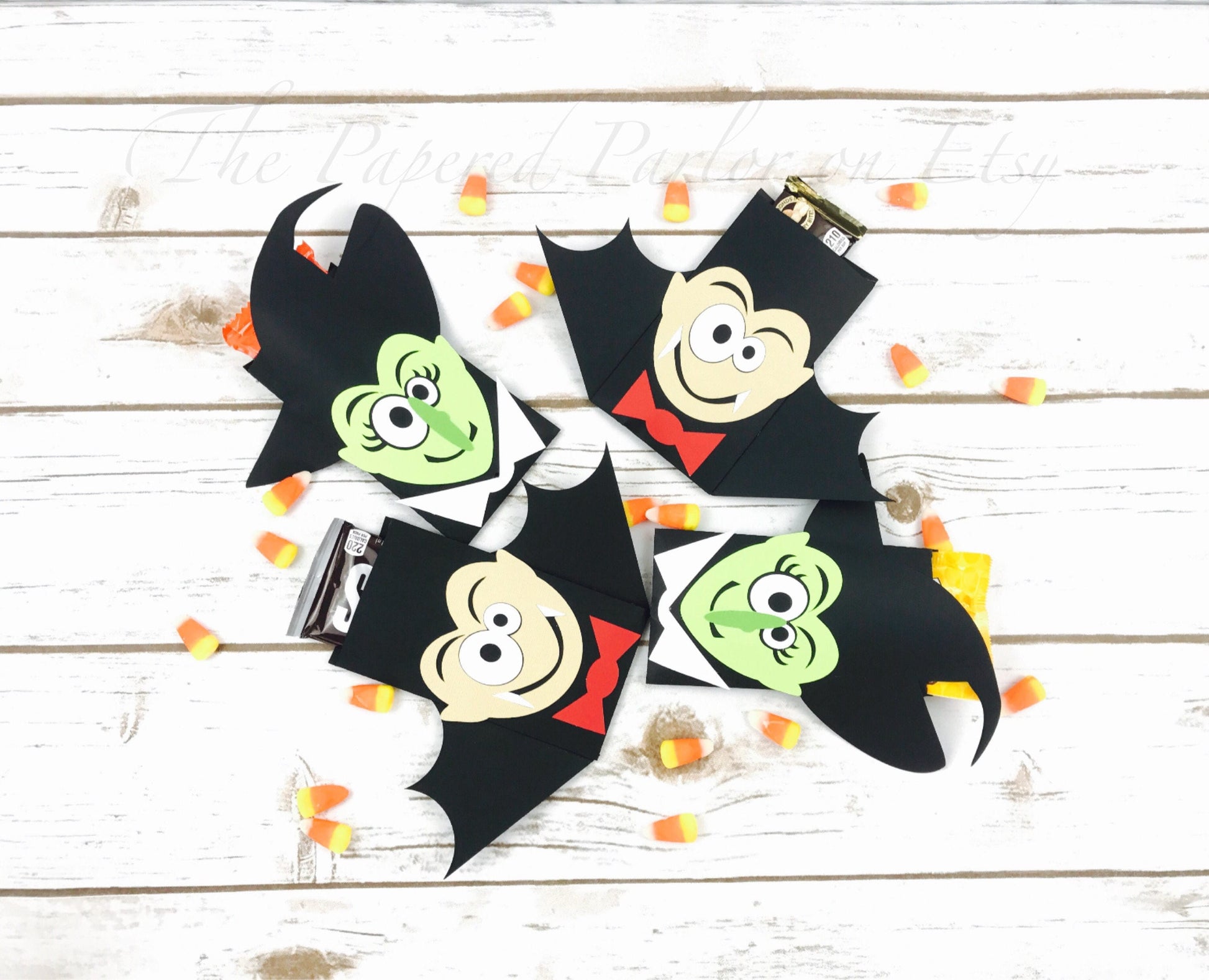 Vampire and witch candy bar holders. The vampire is presented to be in a black suit with a red bow tie while the witch is presented with a green face and a cute witch hat. The holders can also be used as a utensil holder.